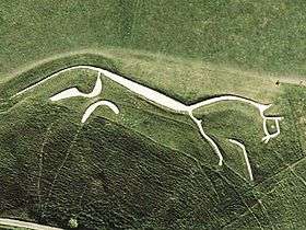 A stylised figure of a white horse cut into the hillside.