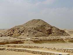 A ruined mass of bricks, sand and rocks resembling an earthen mound