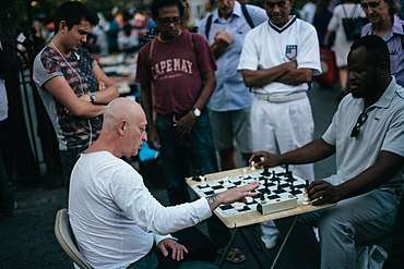 Two seated men playing chess with several spectators