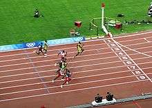 Eight men approach the finishing line of race at a stadium track