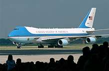 Presidential aircraft taxiing in front of silhouetted crowd.