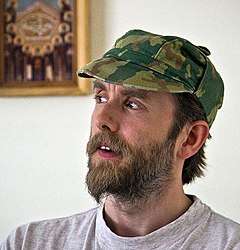 Bearded man in his mid-thirties wearing a camouflage hat