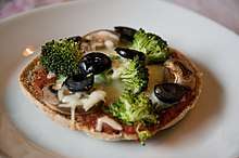 A homemade vegetarian pizza on whole-grain bread with multiple types of vegetables