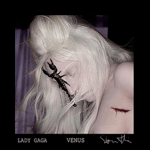 Gaga with her face down and white hair scattered. She has a scorpion attached to her forehead.