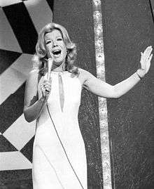 A women wearing a white dress is holding a microphone