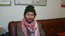 Bearded Asian male wearing a white and red scarf.