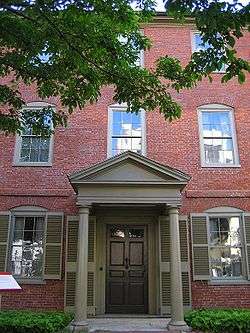 Photograph of the tree-shaded front entrance of the three-story, brick Wadsworth-Longfellow House.
