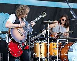 Four-man rock group performing on stage, spotlit,