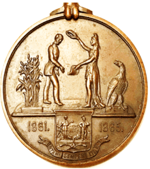 circular medal with grain, two people, an eagle, and dates