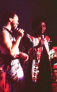 An image of Maurice White and Philip Bailey in Bohemian garb during a stage performance