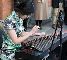 Seated woman playing a guzheng