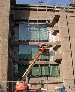 Workers on a lift replace windows on the east facade of the Yale Art + Architecture Building.
