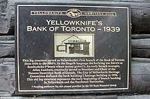 Yellowknife Heritage 2000 - Yellowknife's Bank of Toronto - 1939 - This log structure served as Yellowknife's first branch of the Bank of Toronto from 1938 to the 1950's. In the Dogrib language the building was known as Sombasheko ("house where money grows"). An early branch manager, Allan Lambert, eventually served as President and Chair of the Toronto Dominion Bank of Canada. The City of Yellowknife Heritage Committee declared the bank building a heritage building in 1998. This old log structure represents the early beginning of branch banking in Yellowknife and the Northwest Territories. *Funding assistance for this plaque provided by the TD Bank Financial Group