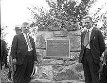 two men standing by a stone pillar with a bronze historical marker for the York Imperial apple