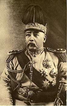 A Chinese man wearing an elaborate military outfit, with a large crown on his head.