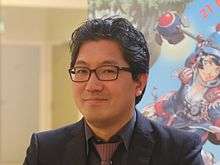 Yuji Naka, a Japanese man in glasses, a black suit, and a red tie, in 2015. He is the co-creator of Sonic the Hedgehog and producer of Sonic Heroes.