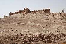 A ruinous stone wall in a desert landscape