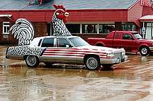 A car with a huge plaster chicken on it